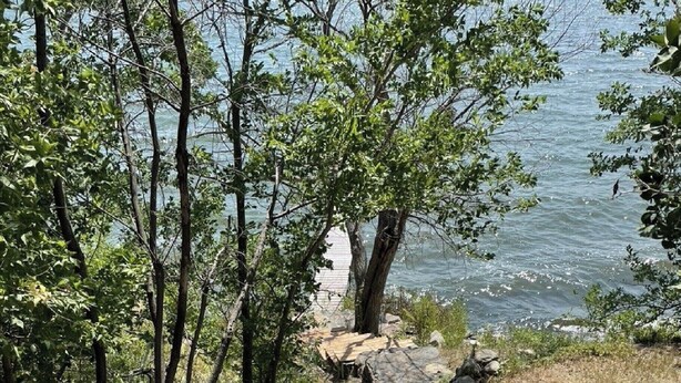 A stone pathway leading to a wooden dock by a lake, surrounded by trees and rocks. - Echo Lake Lakefront Cabin in picturesque Qu’Appelle Valley,  (Fort san)