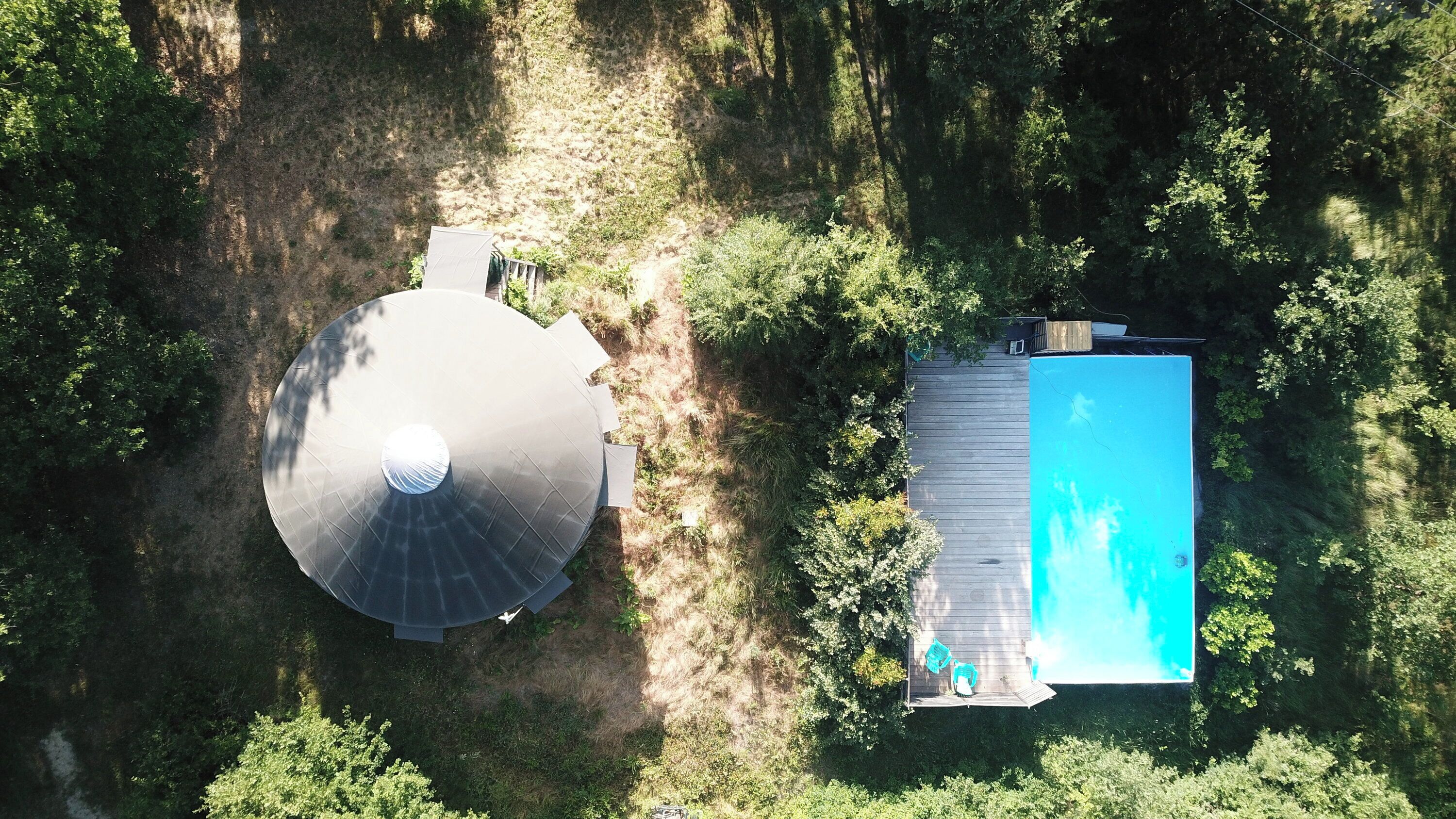 Vista aérea de una propiedad que cuenta con una gran estructura circular, un edificio rectangular y una piscina.