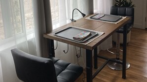 Ruokailutila, jossa on puinen pöytä, mustat tuolit ja ruukussa oleva kasvi.