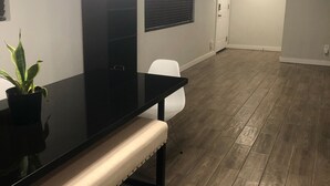 Una habitación con una mesa negra, un banco blanco y una planta en maceta.