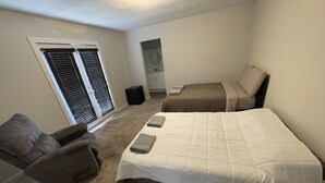 Un dormitorio con dos camas, una silla, una mesita y un armario.