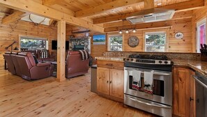 A log cabin interior with a kitchen, dining area, and a fireplace. - Log cabin with game room by skiing & lake (McCall)