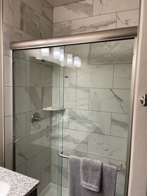 Een bad/douchecombinatie, een haardroger, handdoeken, zeep
