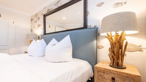Habitación de hotel con cama, mesita de noche, lámpara y papel tapiz con motivos de peces.