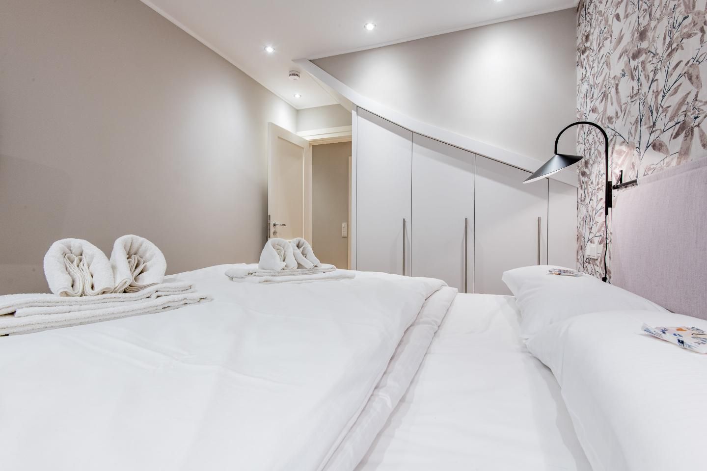 A modern hotel room with a large bed, a wardrobe, and a decorative wall.