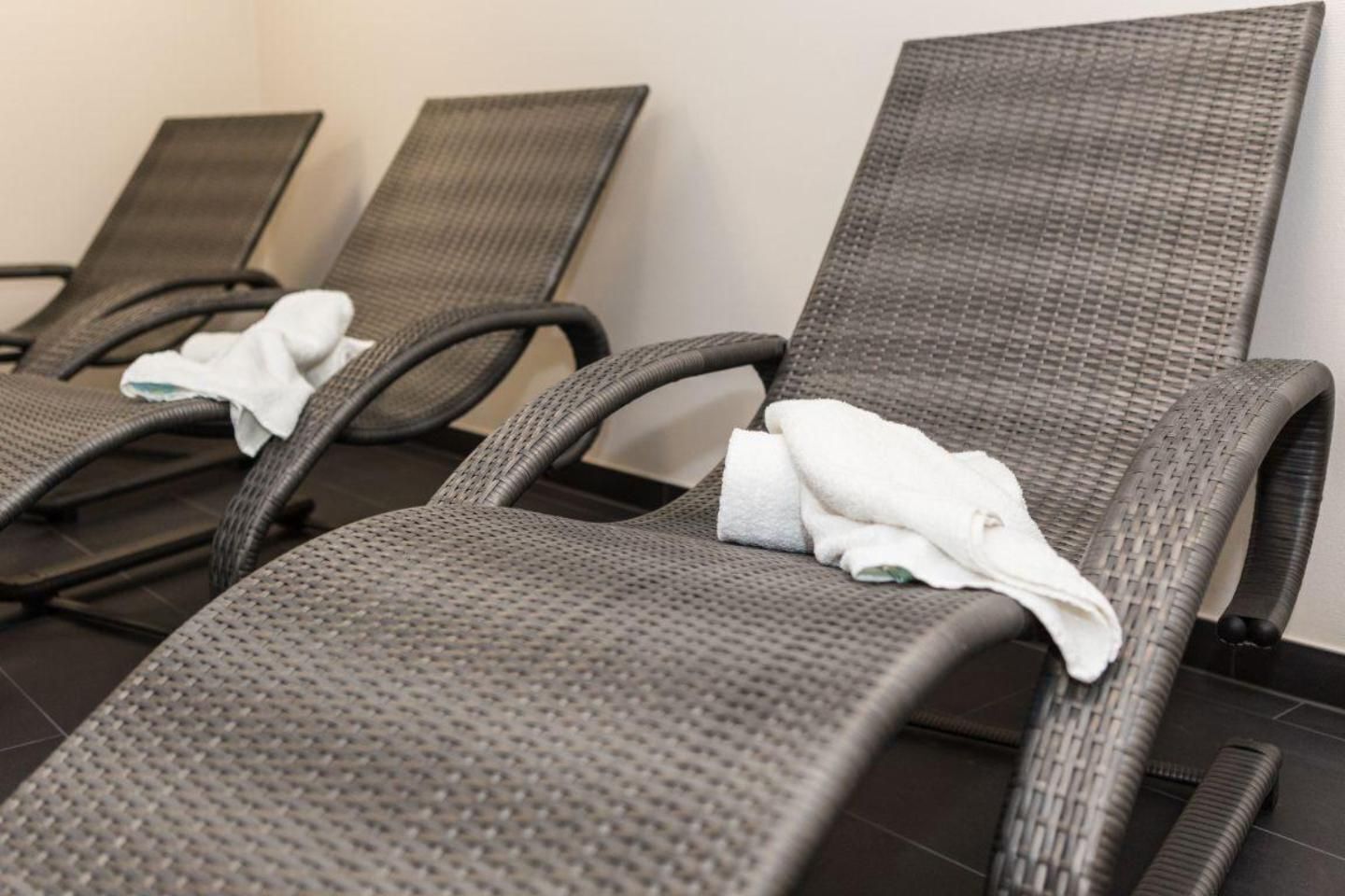 A row of reclining chairs with towels, suggesting a spa or relaxation area.