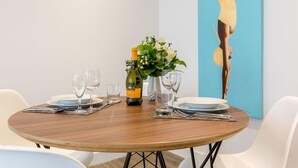 Une table de salle à manger ronde, avec une bouteille de vin, des verres et un vase de fleurs.