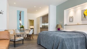 Une chambre d’hôtel moderne dotée d’un grand lit, d’un coin repas avec une table et des chaises, d’une cuisine et d’un espace de détente avec un canapé.
