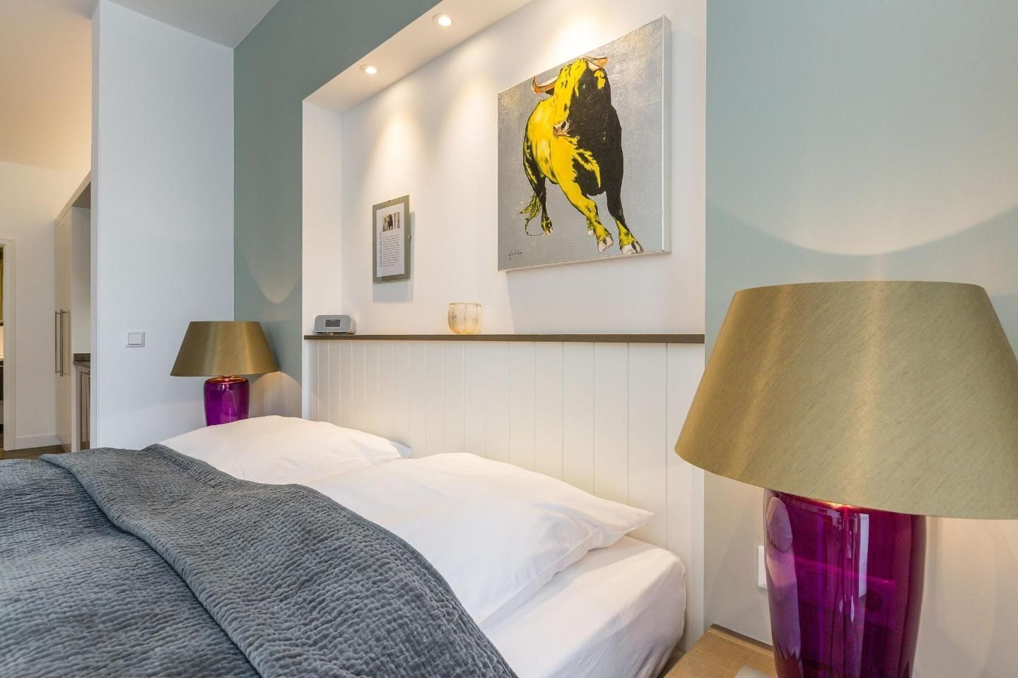 Una habitación de hotel con una cama, una mesita de noche, una lámpara y un cuadro en la pared.