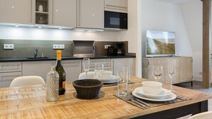A modern kitchen with a dining area set for a meal. - Art your Life - Residence, Whg. 9 Iliya - Art your Life - Residence Seeburg (Sylt)