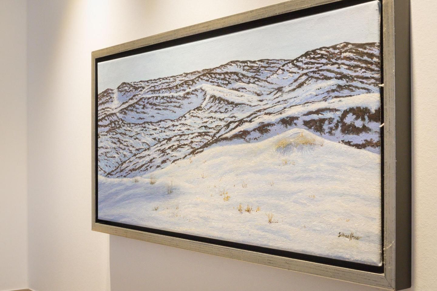 Un tableau encadré représentant un paysage de montagne enneigé.