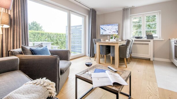 A modern living room with a sofa, coffee table, and dining area. - Ringhoog-Hüs, Whg. 2 "Waldidyll" - Ringhoog Hüs (Sylt)