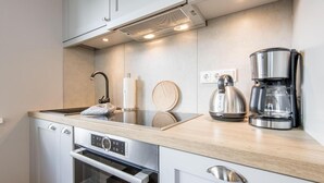 A modern kitchen with a stainless steel kettle, coffee maker, and built-in oven. - Ringhoog-Hüs, Whg. 2 "Waldidyll" - Ringhoog Hüs (Sylt)