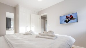 A hotel room with a large bed, two doors, a television, and a view of a balcony. - Ringhoog-Hüs, Whg. 2 "Waldidyll" - Ringhoog Hüs (Sylt)