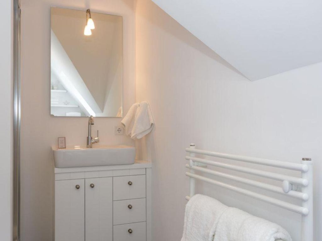 Une salle de bain avec un lavabo blanc, un miroir et un porte-serviettes.