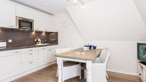 A modern kitchen with white cabinetry, a wooden dining table, and a built-in oven.