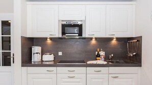 A modern kitchen with white cabinets, a dark countertop, and a built-in oven.