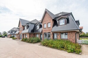 Une rangée de maisons modernes en briques, dotées de toits à deux versants et de grandes fenêtres.
