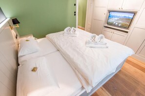 A hotel room with a bed, a television, and a green wall. - Villa Maybach, Whg. 4 Grüner Wim - Villa Maybach (Sylt)