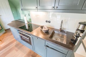 A kitchen with a built-in oven, a sink, and a coffee maker. - Villa Maybach, Whg. 4 Grüner Wim - Villa Maybach (Sylt)