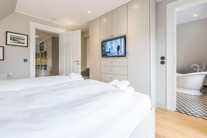 A hotel room with two beds, a TV, a bathroom with a bathtub, and a walk-in closet. - Villa Maybach, Whg. 6 - Villa Maybach (Sylt)