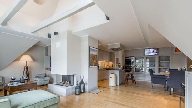 Un ampio loft con soffitto alto, camino, angolo cottura e zona pranzo.