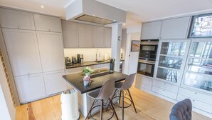 Una cucina moderna con mobili grigi, un'isola centrale con sedie ed elettrodomestici integrati.