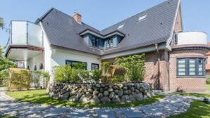 Una casa a due piani con fondamenta in pietra, tetto spiovente e un'ampia finestra.