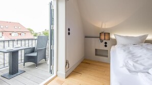 Una stanza piccola e moderna con un letto, un tavolo con sedie e un balcone.