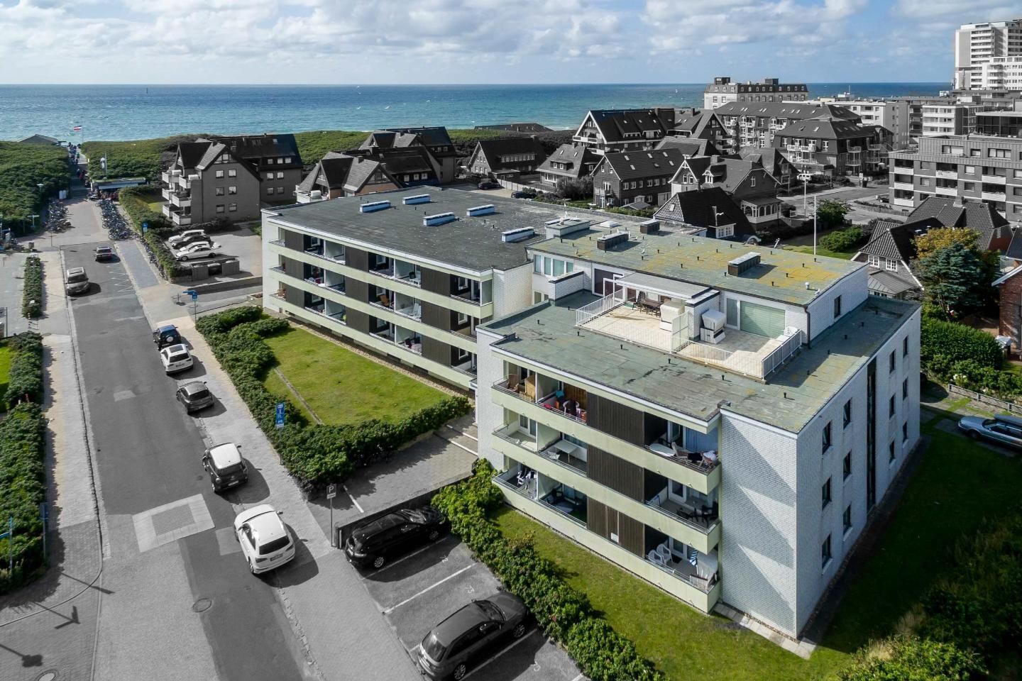 Ein modernes, mehrstöckiges Gebäude mit flachem Dach, Parkplatz und Meerblick.
