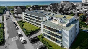 Ein modernes, mehrstöckiges Gebäude mit flachem Dach, Parkplatz und Meerblick.