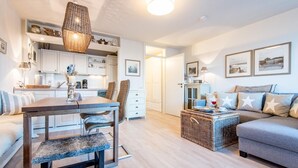 Ein modernes Wohnzimmer mit Essbereich, einer Couch, einem Couchtisch und einer Küche im Hintergrund.
