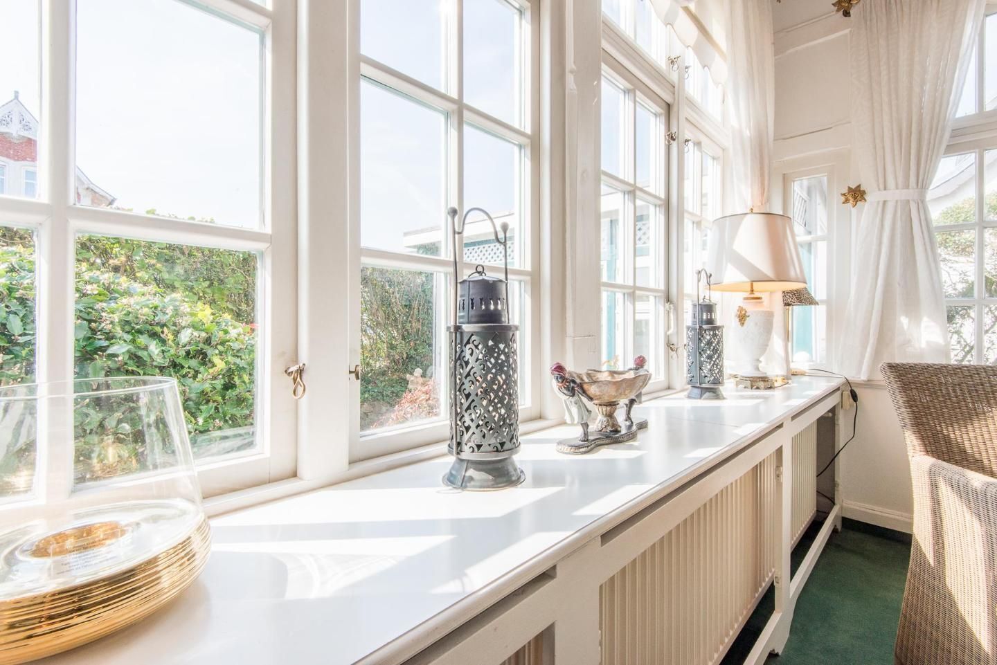 A bright room with large windows, a radiator, and a wicker chair.