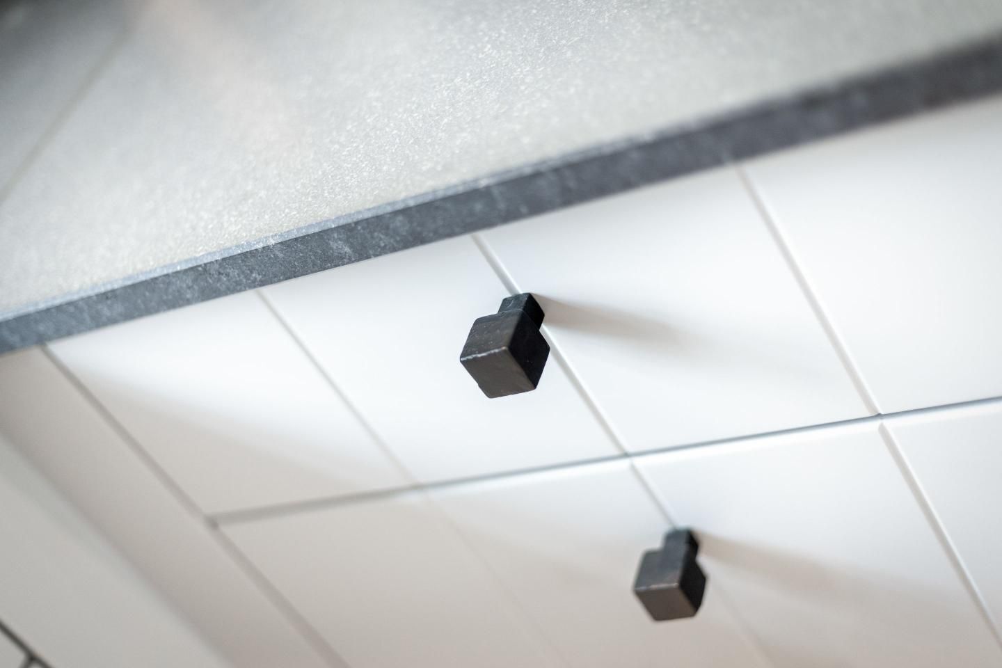 Un plafond recouvert de carreaux, avec deux luminaires noirs.
