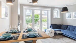 A dining area with a table set for four, a blue sofa, and a view of the outdoors.