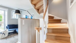 A modern interior with a staircase, a blue sofa, a table, and a lamp.
