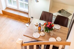Een eetgedeelte met een houten tafel voor vier personen, compleet met borden, glazen en een fles.