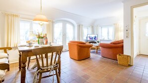 Ein helles Wohnzimmer mit Essbereich, Fernseher und Kamin.