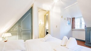 Ein Hotelzimmer mit zwei Betten, einer Lampe, einem Schrank und einem Fenster mit Vorhängen.