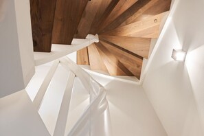 A modern staircase with white railings and wooden beams. - House at Steinmannstraße 77, half of House A (Sylt)