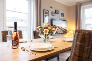 A dining table set with plates, cutlery, a bottle of wine, and a vase of flowers. - House Steinmannstraße 77, half of the house A (Sylt)