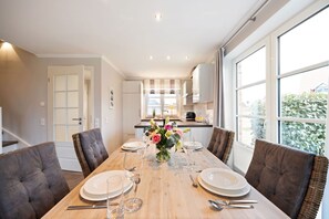 Un coin repas avec une table en bois dressée pour quatre personnes, entourée de chaises rembourrées.