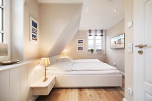 Une chambre moderne avec un lit, des tables de chevet, une fenêtre avec des rideaux et un téléviseur fixé au mur.