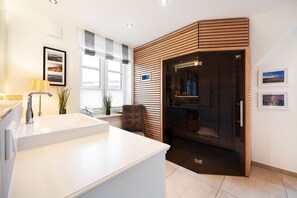 A modern bathroom with a white sink, a mirror, and a wooden panel wall. - House Steinmannstraße 77, half of the house A (Sylt)