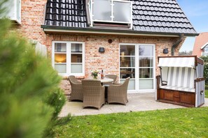 A brick house with a patio, outdoor seating, and a large window. - House at Steinmannstraße 77, half of House A (Sylt)
