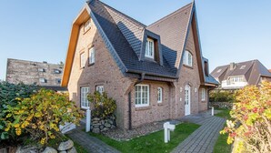 Une maison moderne avec un toit en pente, une façade en briques et une allée pavée.