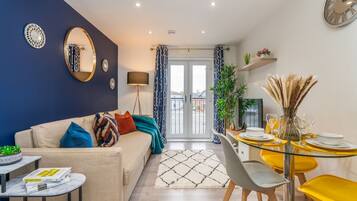 A modern living room with a sofa, coffee table, and dining area with yellow chairs and a glass table.