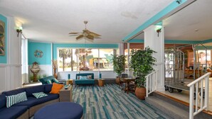 A spacious living area with a large window, a ceiling fan, and a dining area with a table and chairs. - OCEAN VIEW SUITE WITH FULL KITCHEN (Daytona Beach)