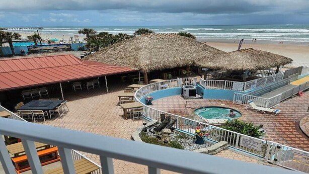 A resort with a pool area, thatched-roof structures, and a view of the beach. - OCEAN VIEW SUITE WITH FULL KITCHEN (Daytona Beach)