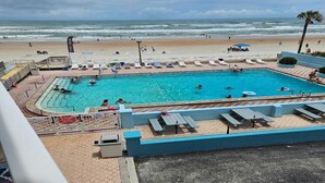 A pool area with lounge chairs and a view of the beach. - OCEAN VIEW SUITE WITH FULL KITCHEN (Daytona Beach)